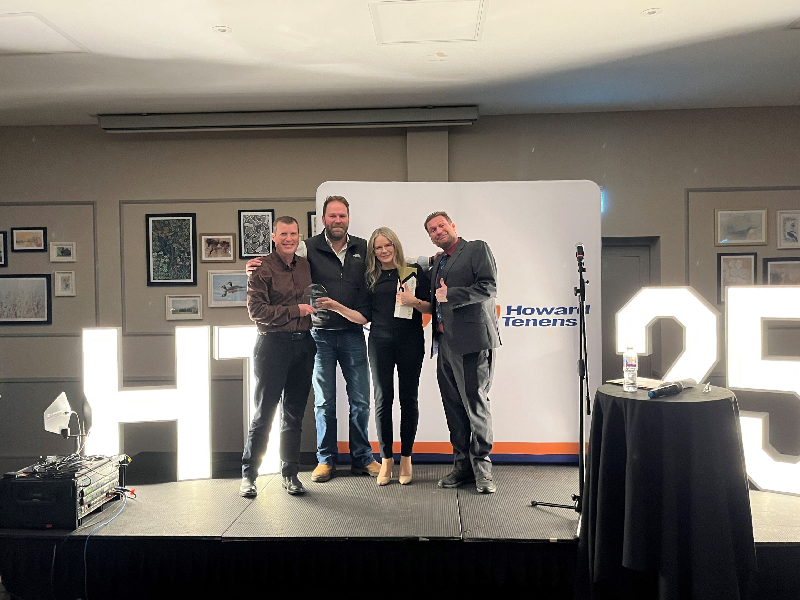 Award winner stood on stage with stakeholders