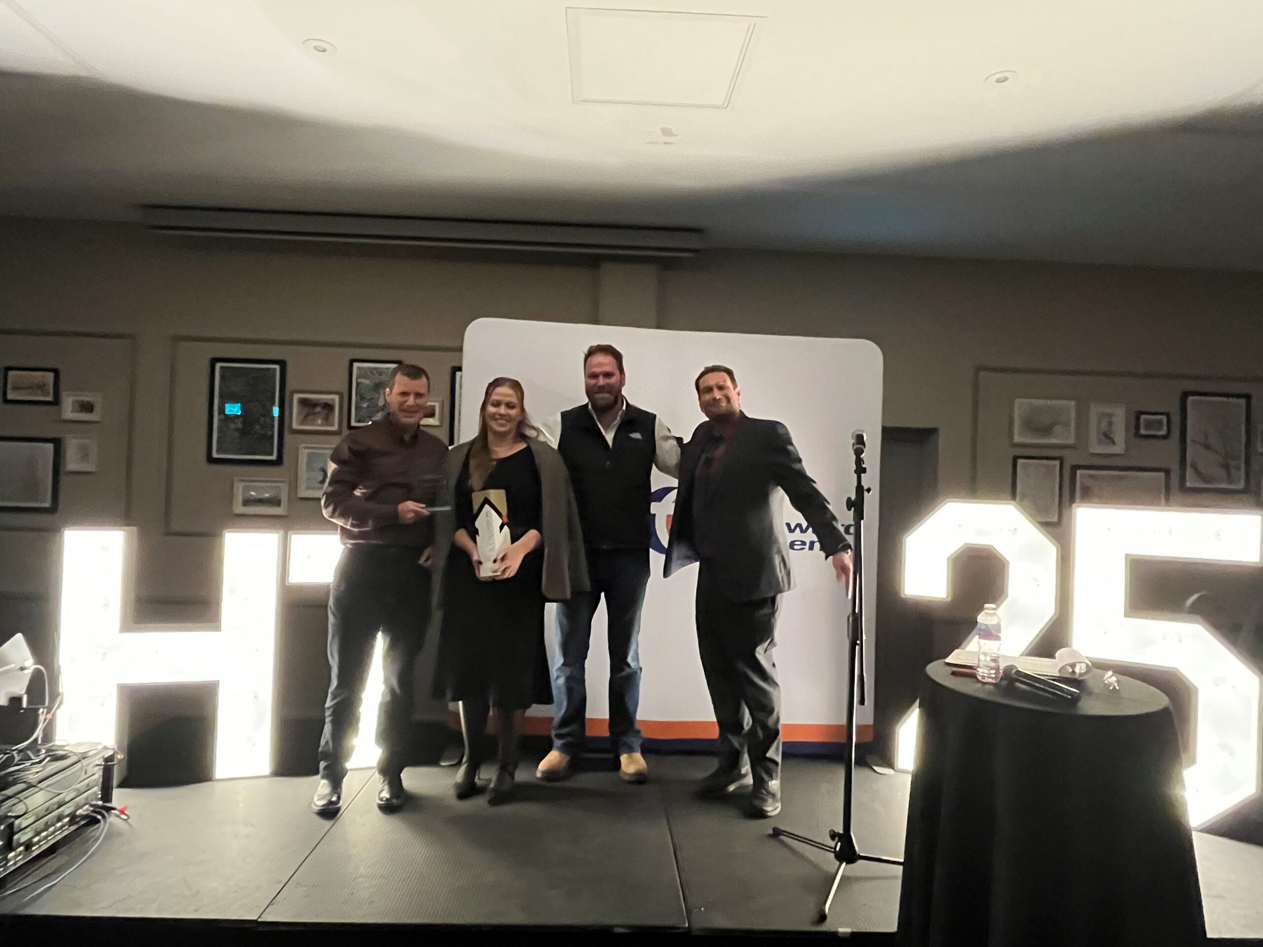 Award winner stood on stage with stakeholders