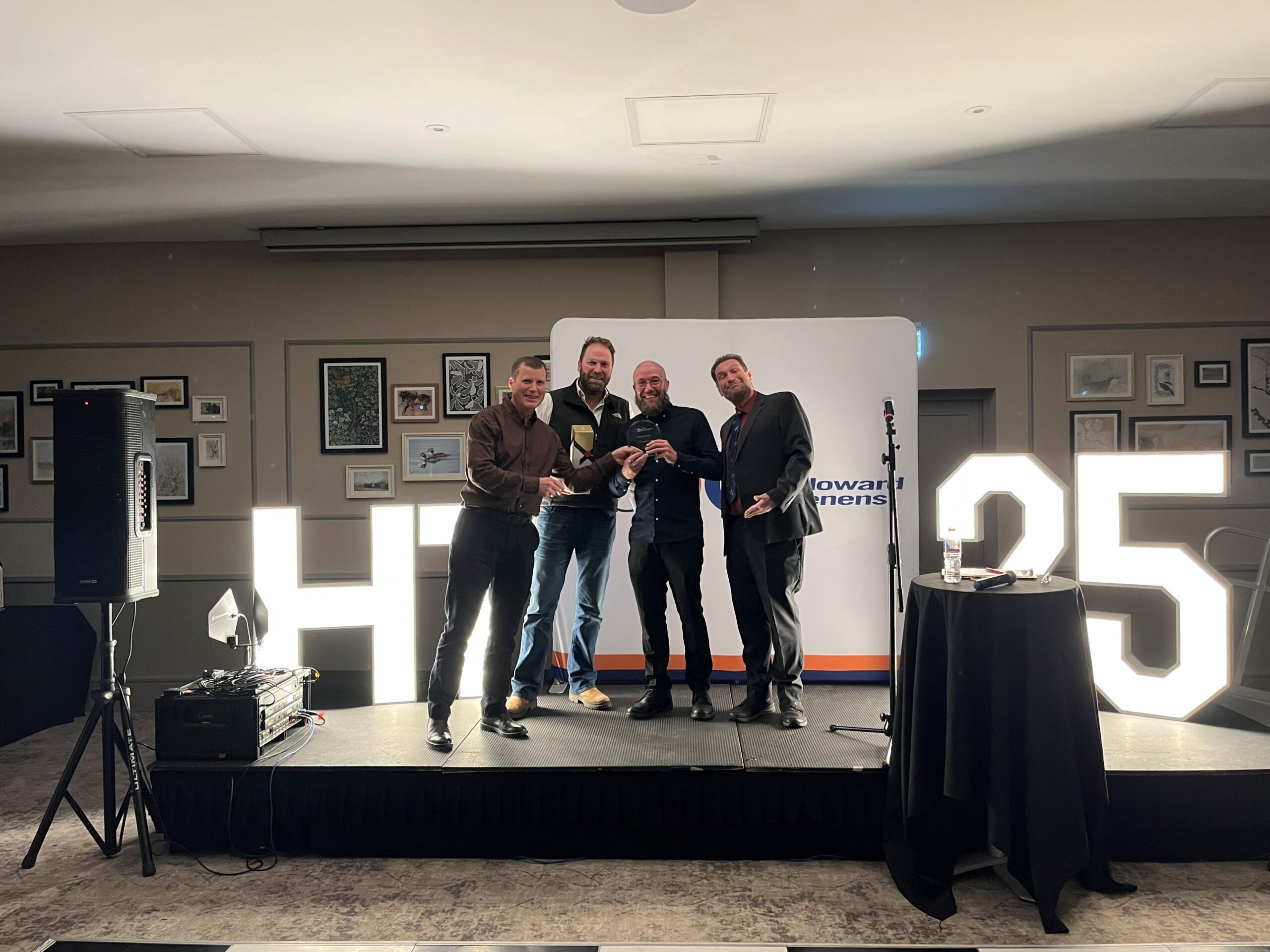 Driver Paul Whitehead on stage holding his award with stakeholders