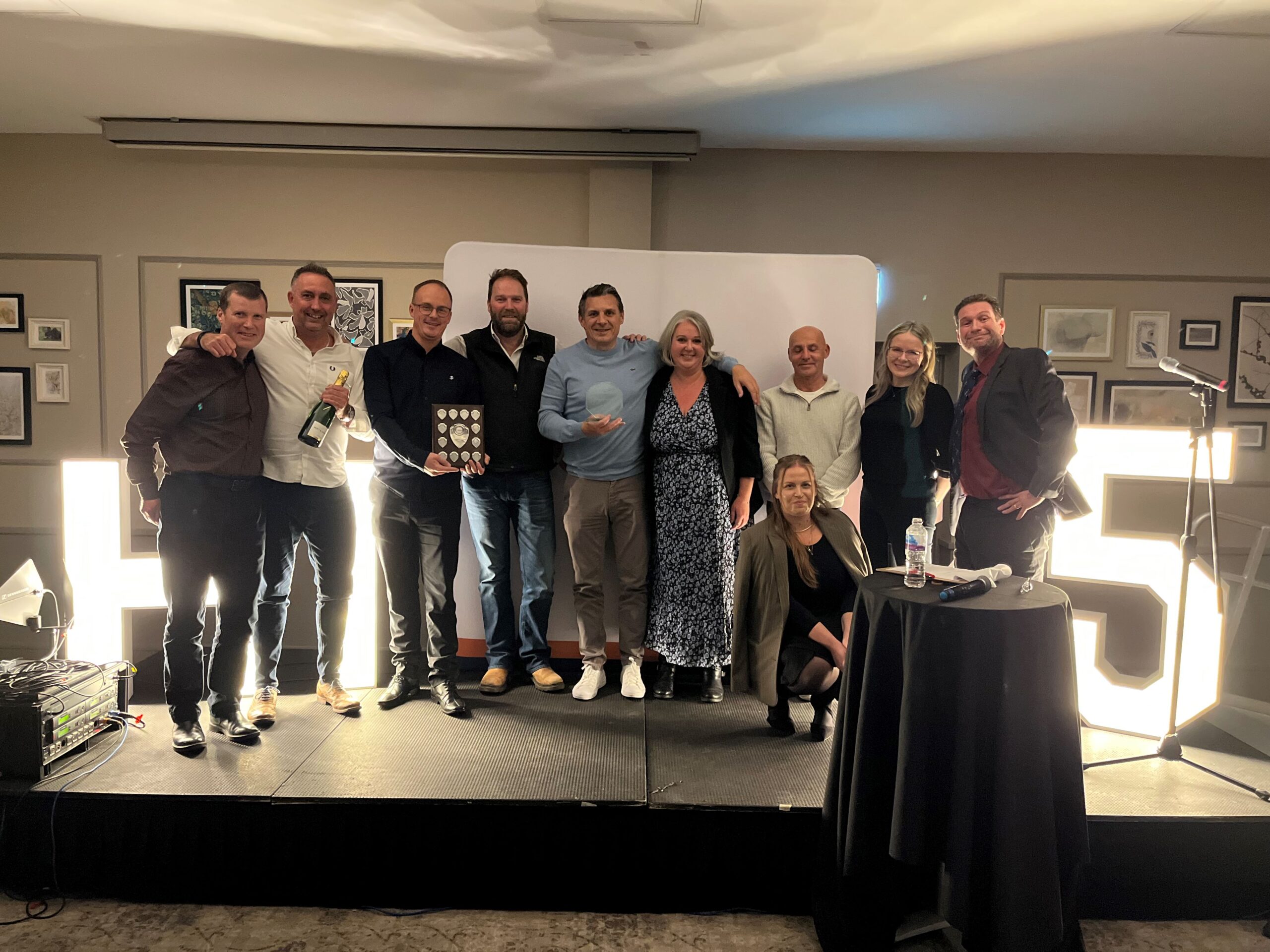 Award winner stood on stage with stakeholders