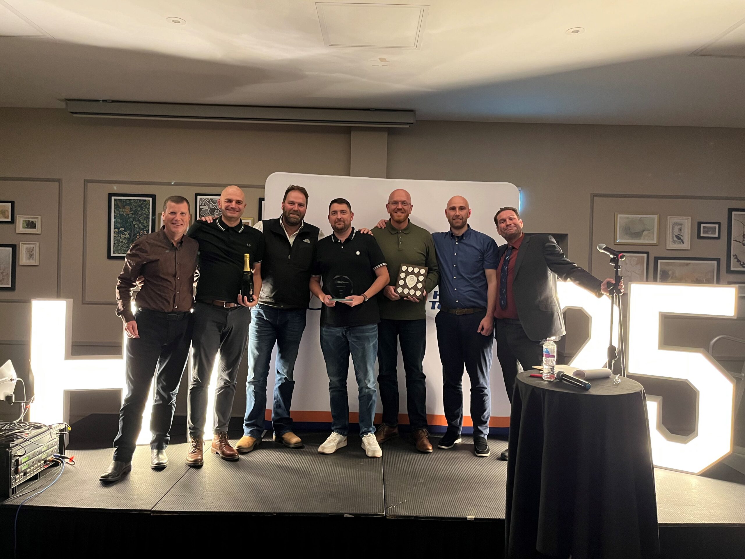 Award winner stood on stage with stakeholders