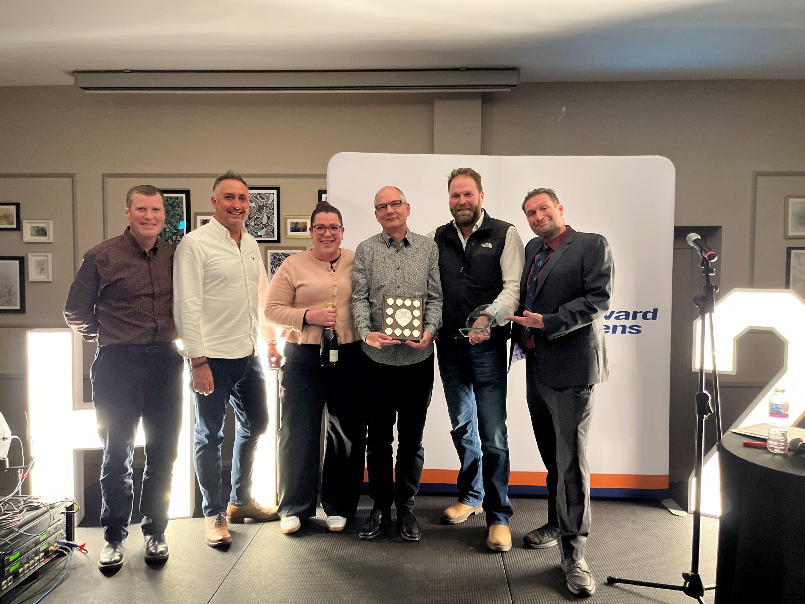 Award winner stood on stage with stakeholders